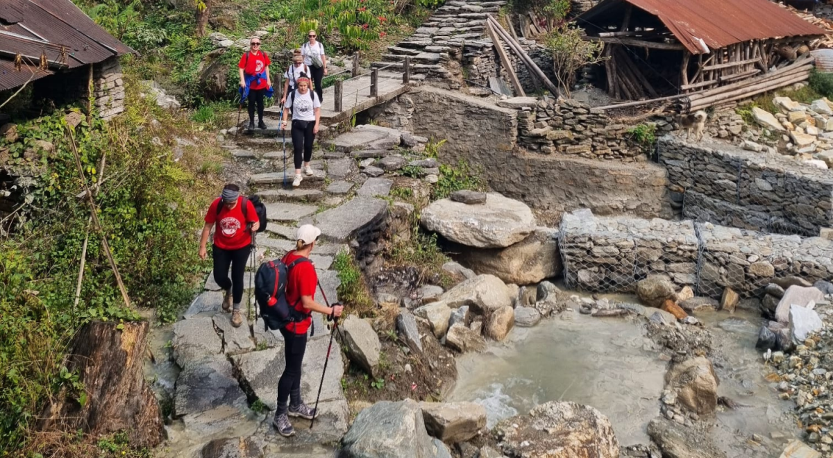 Women leaders of Flight Centre Travel Group scale stone steps by a mountain creek
