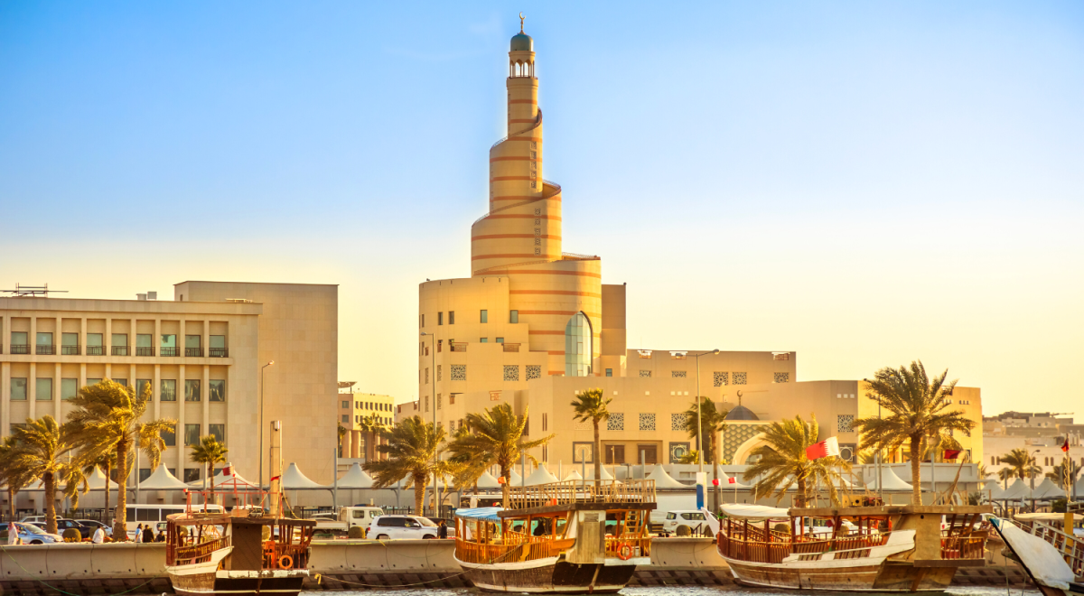Unique spiral architecture on the waterfront in Qatar lined by palm trees and boats