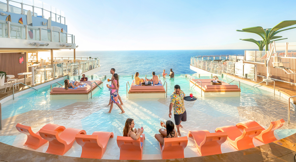 People relax by the pool on a cruise ship deck with ocean views