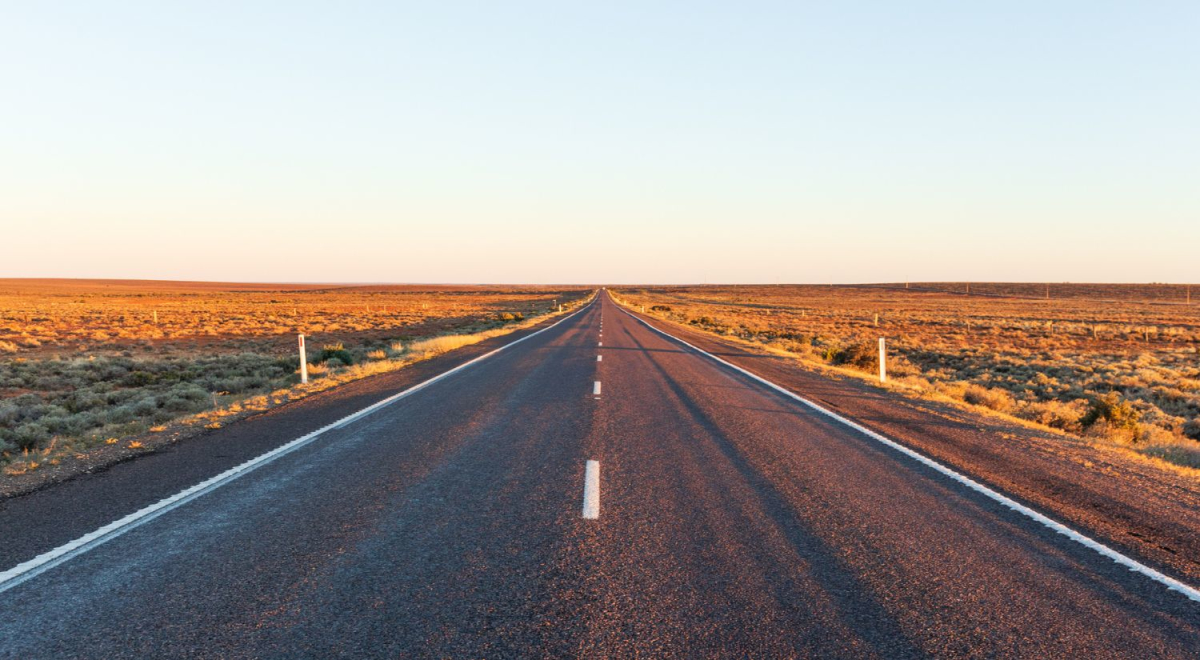 An image take by someone standing in the middle of a long quiet road.