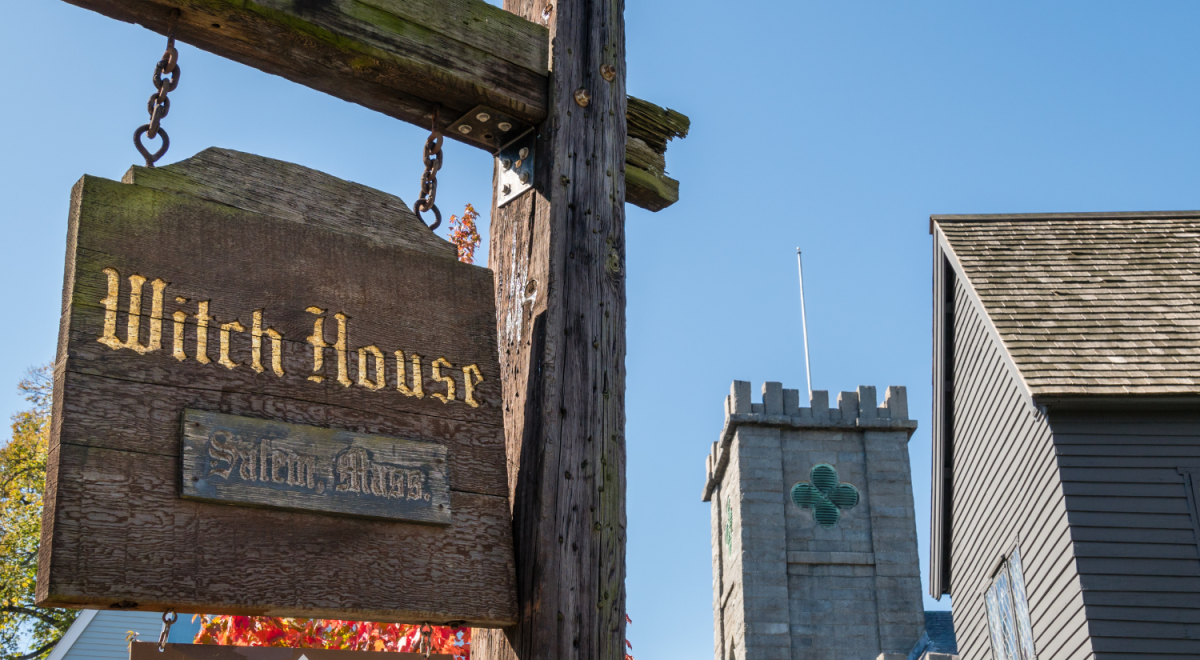 A wooden sign that reads 'Witch House' hangs from chains in Salem Massachusetts