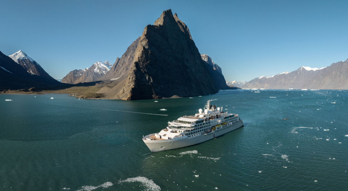 A Silversea Cruises' ship in a remote location with rugged mountains.