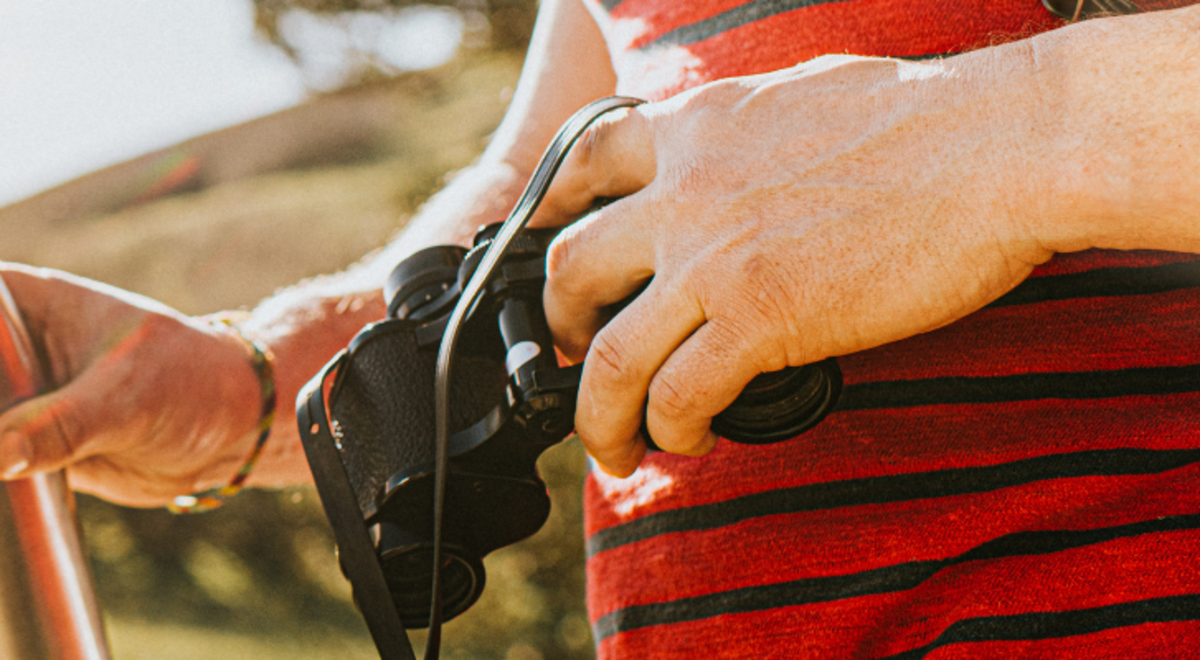 Close up of a person walking and carrying a water bottle and binoculars
