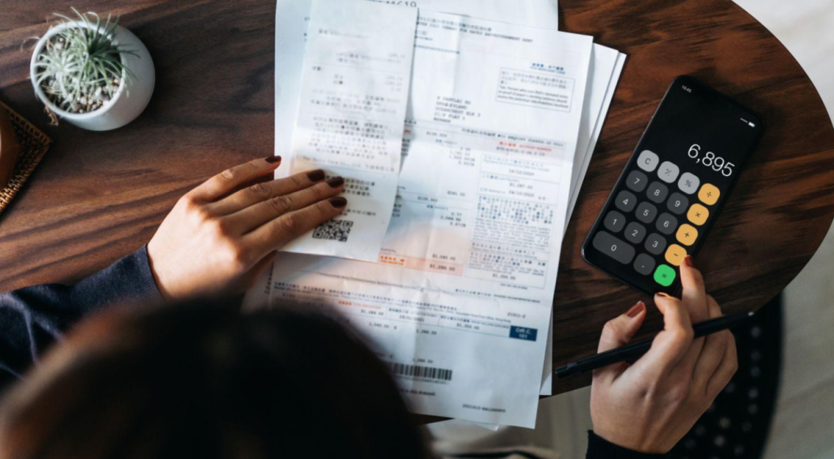 Top view of person at table looking at receipts and using a calculator 