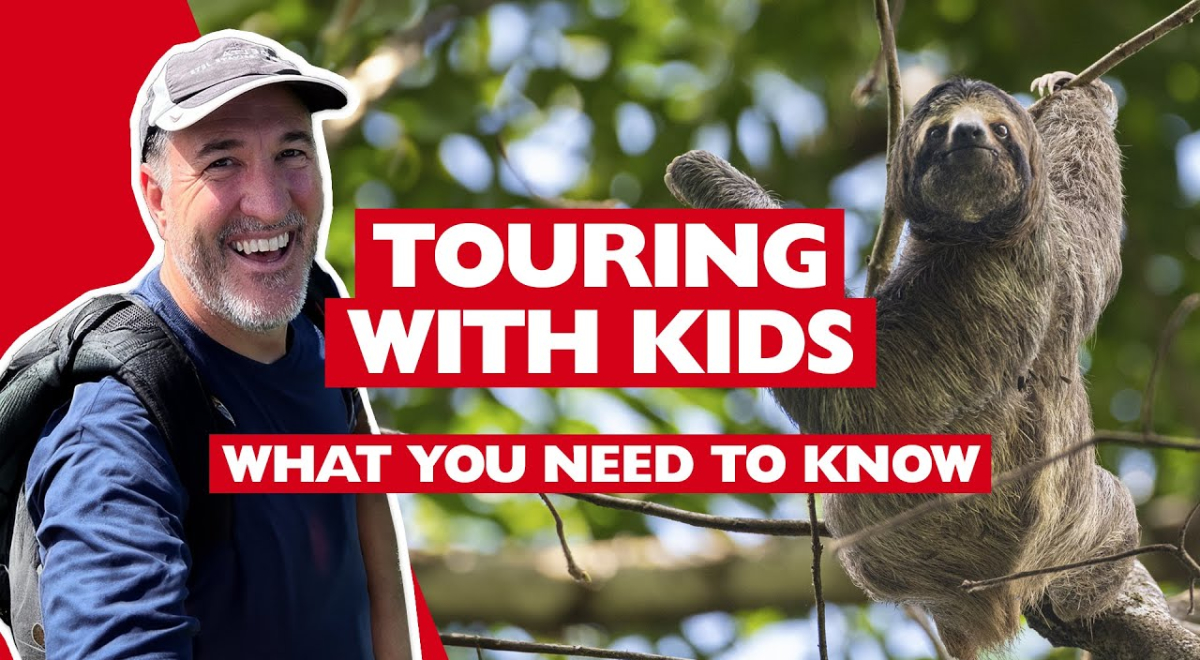 Man with backpack on tour with a sloth in a tree