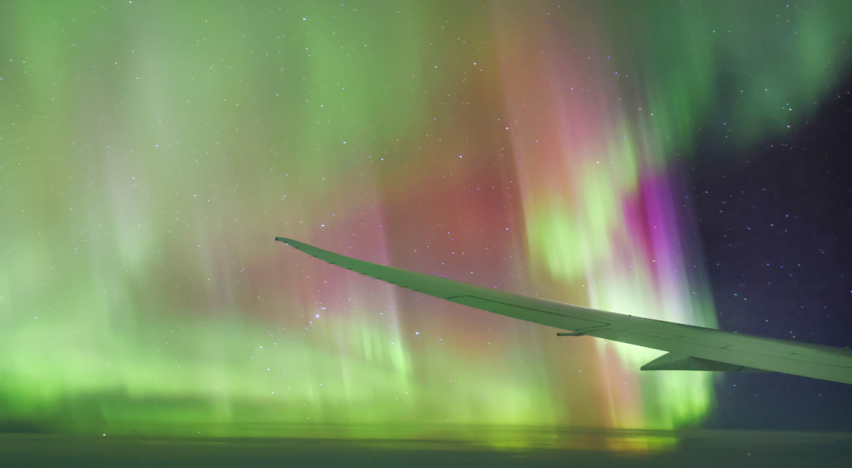 Plane wing flying through Aurora Australis