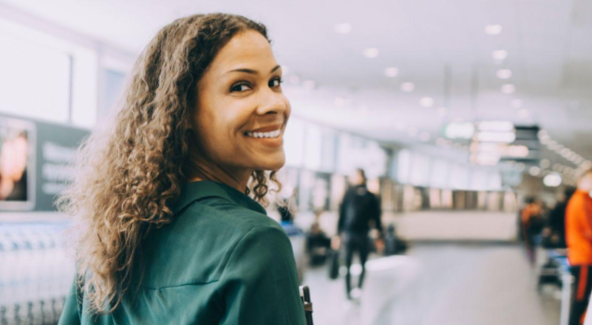 Woman walking through an airport looking back at the camera