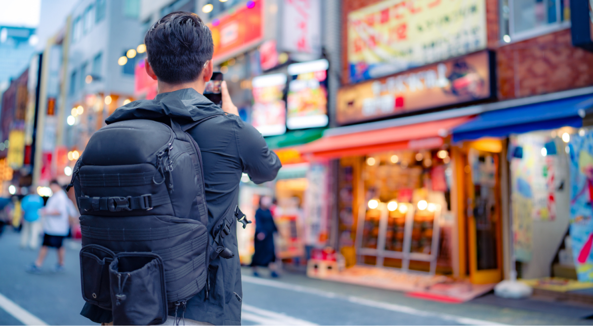 man wearing large backpack taking photo on street in japan