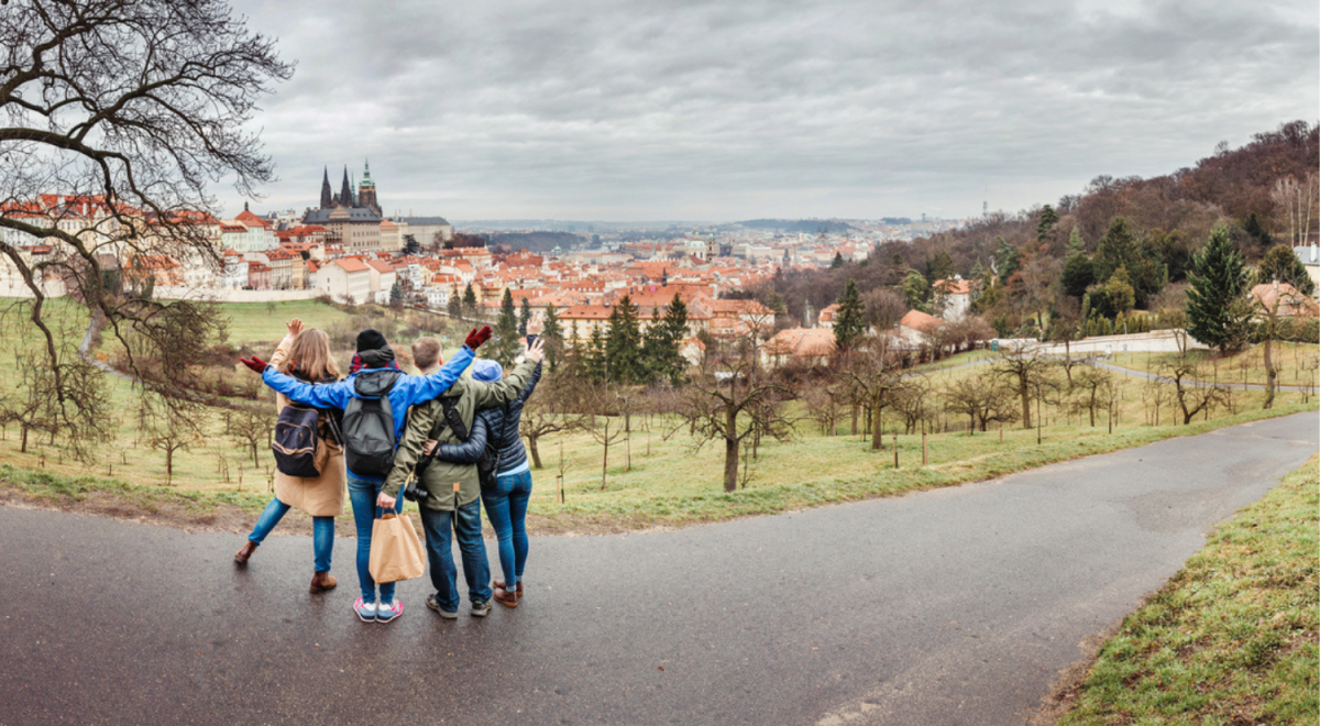 Four friends with arms around each other standing on road looking out to old town 