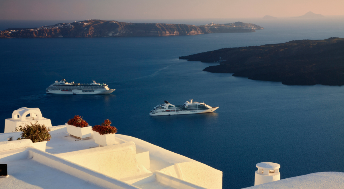 two cruise ships in sea with white buildings overlooking