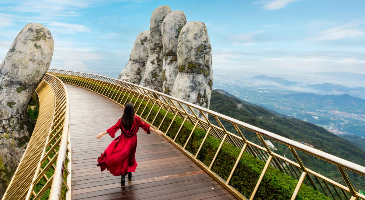 lady in red dress twirling around on bridge in the sky vietnam