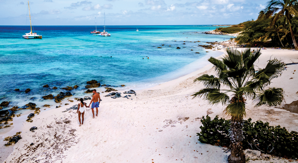 A couple walking on a white-sand beach in Aruba
