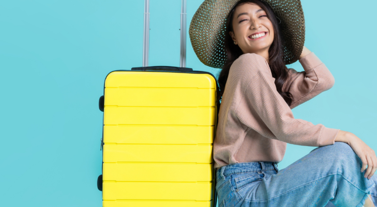 Woman leaning against her yellow suitcase 