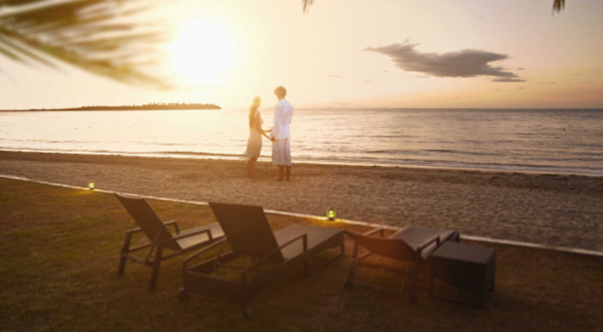 Couple holding hands on the beach at sunset