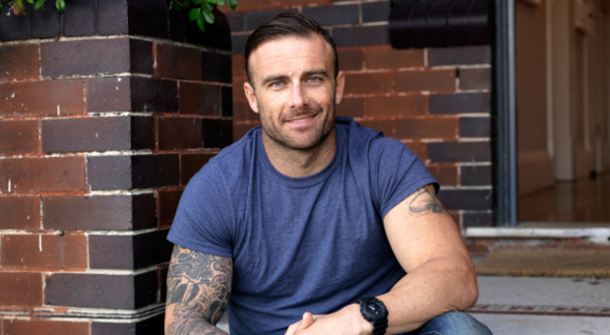 Guy sitting in the porch smiling in the photo