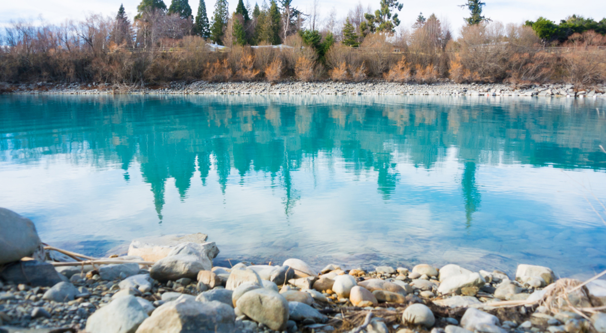 the crystal blue waters of lake tekapo surrounded by white and beige stones