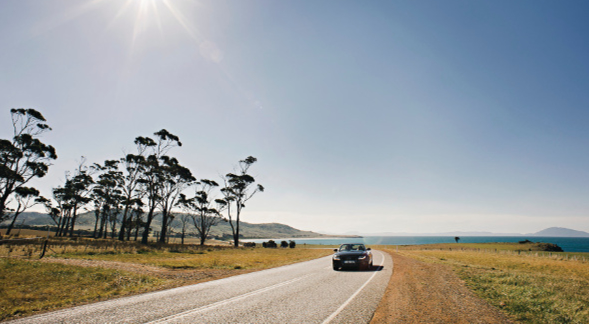 A road through Tasmania with a lake and mountains in the background