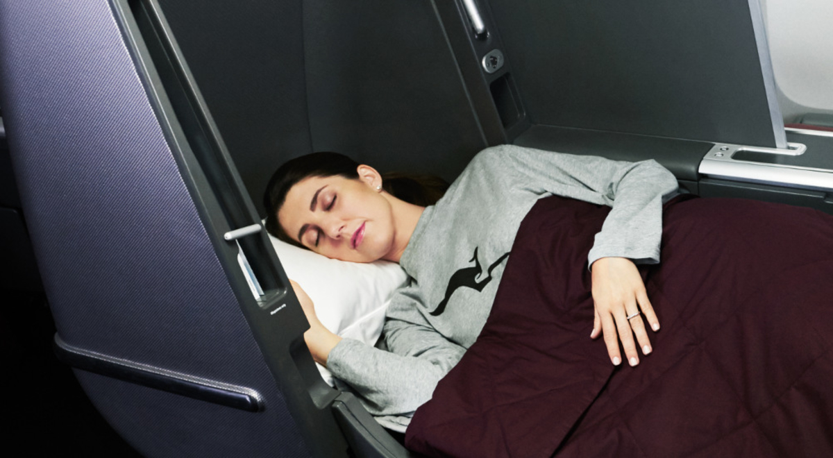 A woman sleeping on her Qantas Business Class lay flat seat