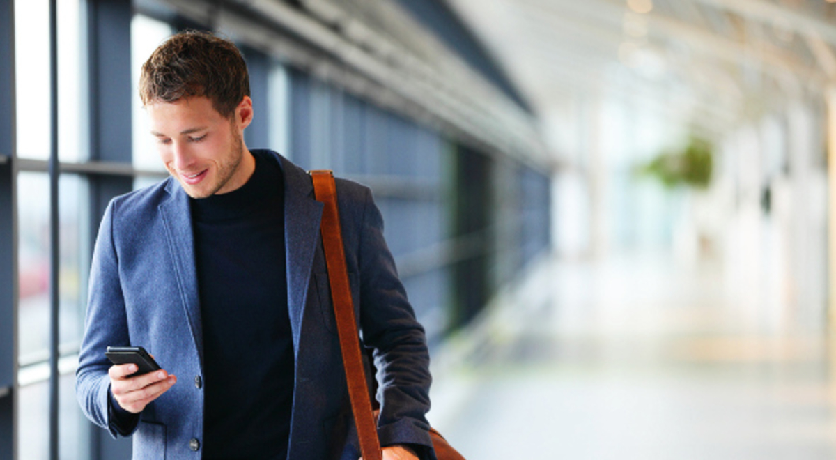 a guy scrolling through his phone while walking around the airport