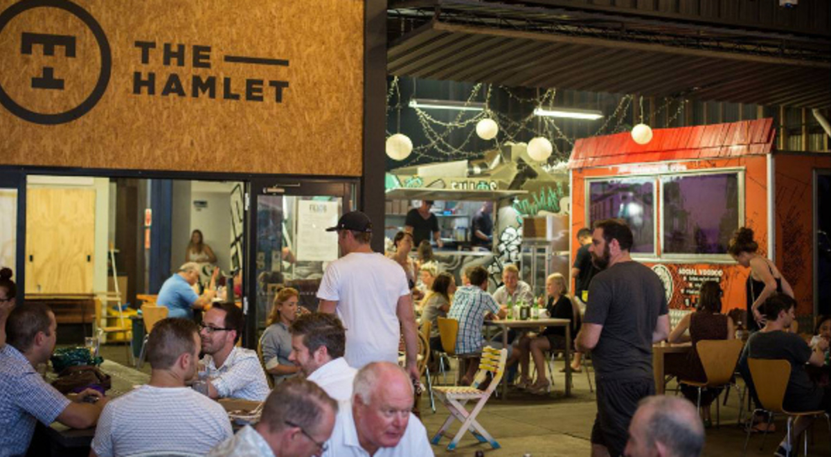 People sitting and eating around food trucks