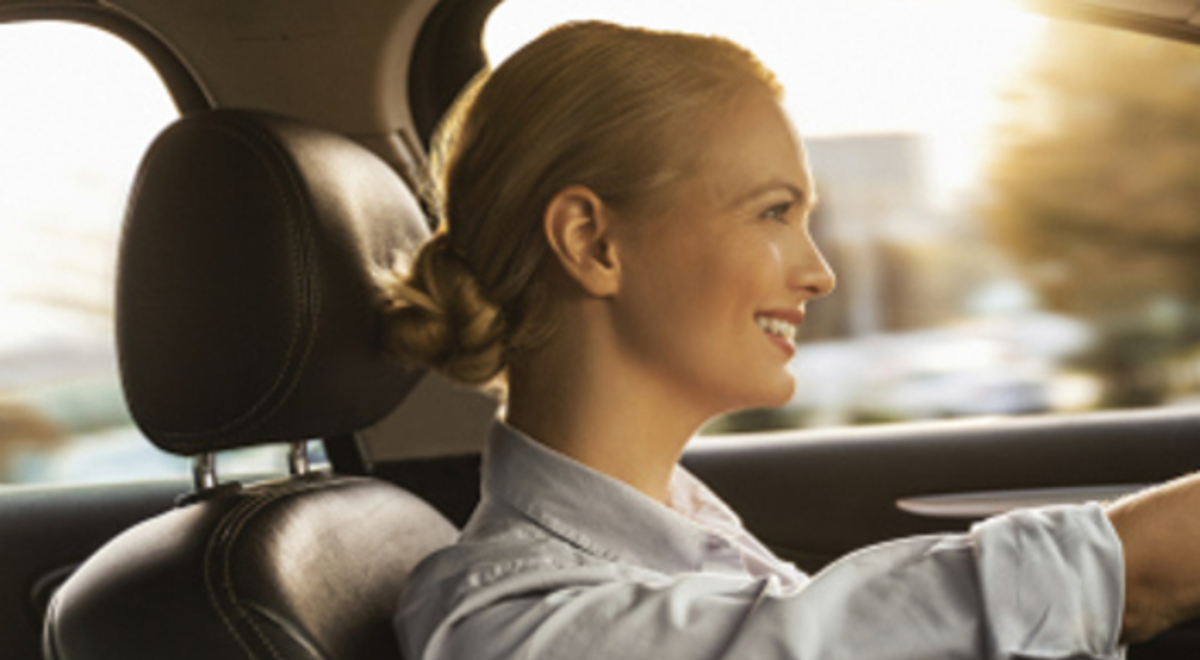 a girl with a bun happily driving her car
