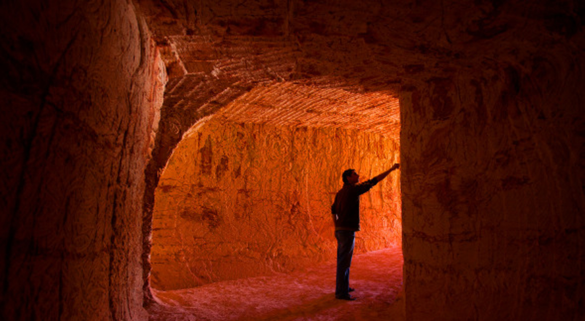 a man wandering along the tunnel and touching its walls
