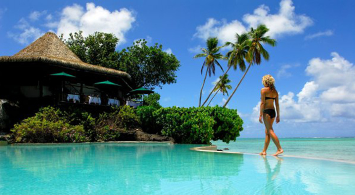 Woman standing on the ledge of a large, clear blue pool 