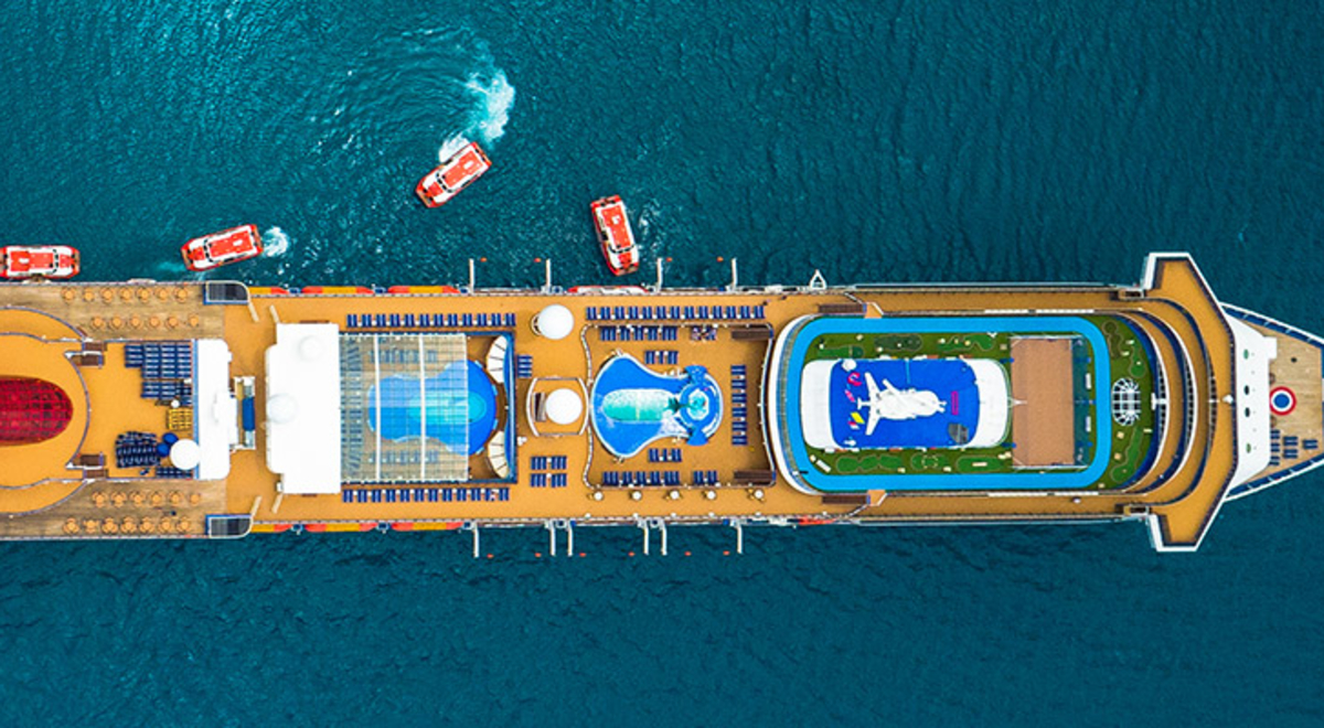 Aerial view of a huge cruise ship at sea with motor boats stationed on its side