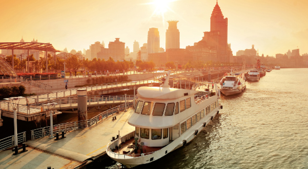 A boat on Huangpu River in shanghai at sunset with city buildings in the background 