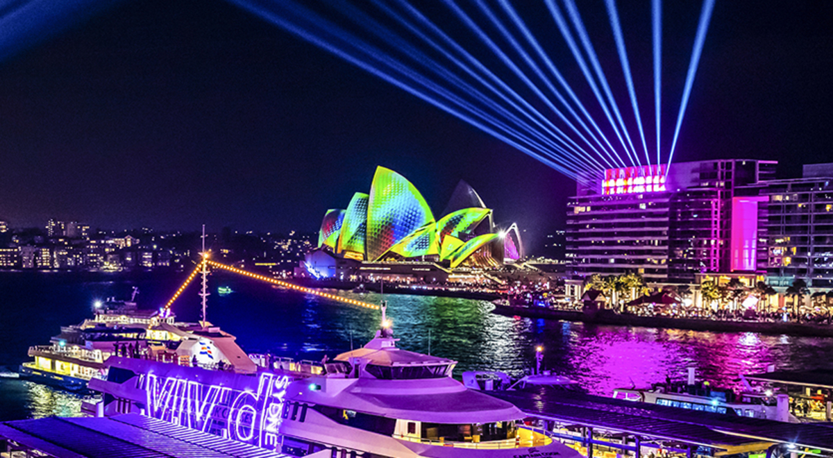 Sydney Harbour at night with colour lights illuminating the Sydney Harbour Bridge and the Sydney Opera House