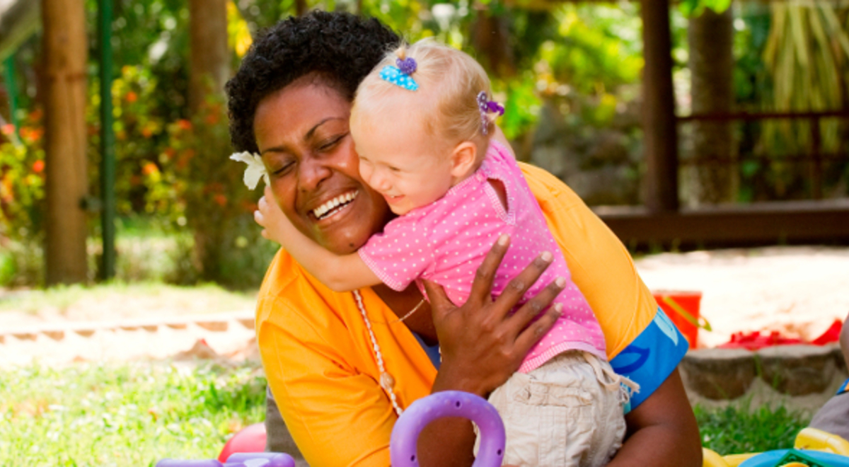 Nanny holding a baby while playing