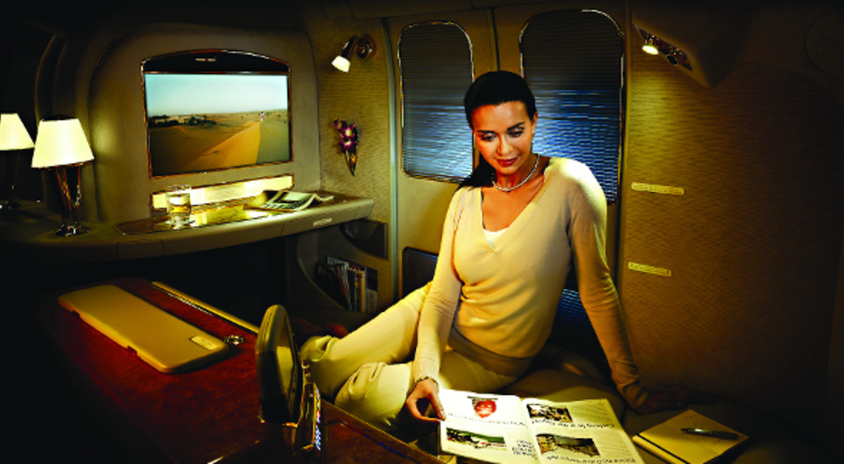 Woman sitting comfortably in a luxurious plane seat reading a magazine