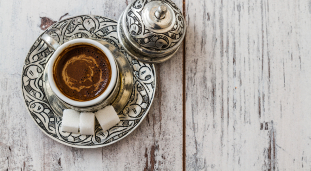 Fortune turkey coffee in an intricately designed cup and saucer with three blocks of white sugar on the side