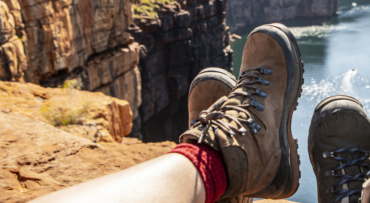 friends showing their tactical boots while sitting on the top of their hike