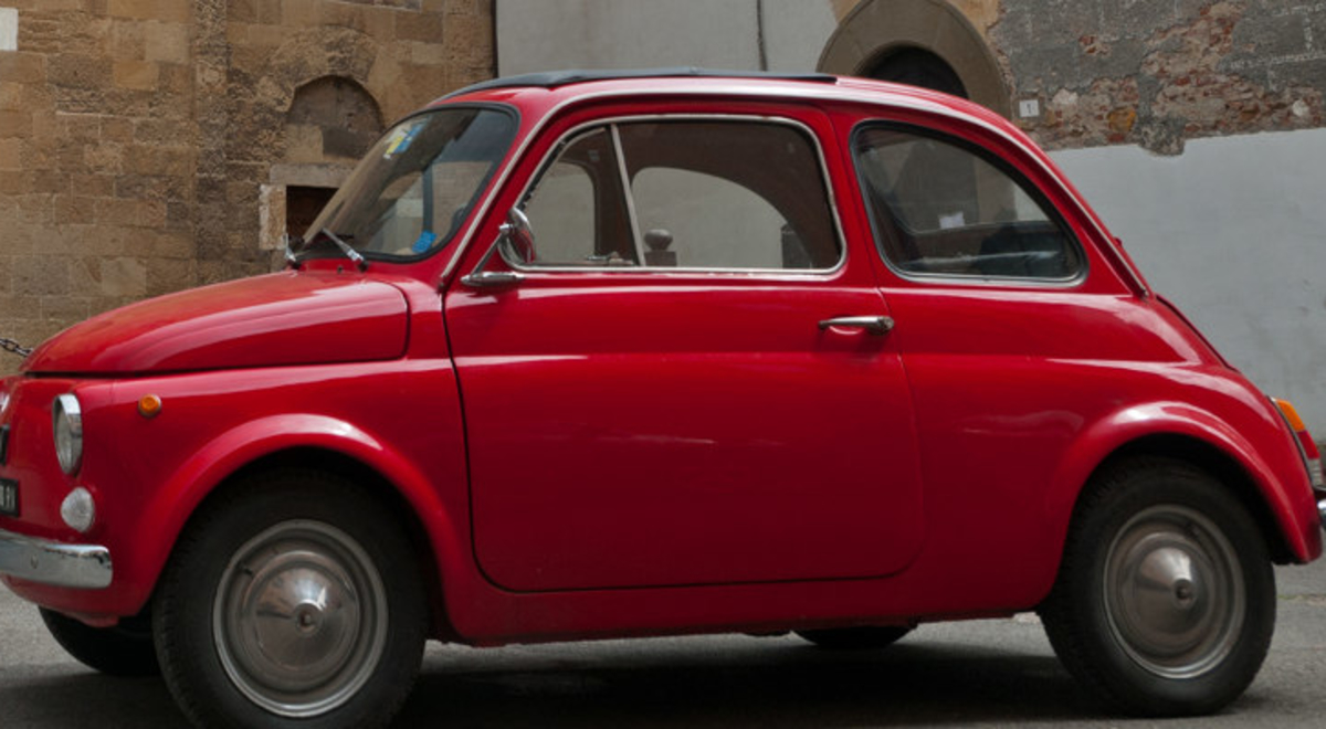 A clean, small, red car parked on an old street