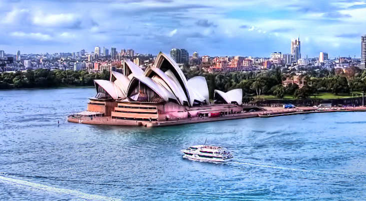 A view of Sydney Harbour from above with boats sailing past the Sydney Opera House