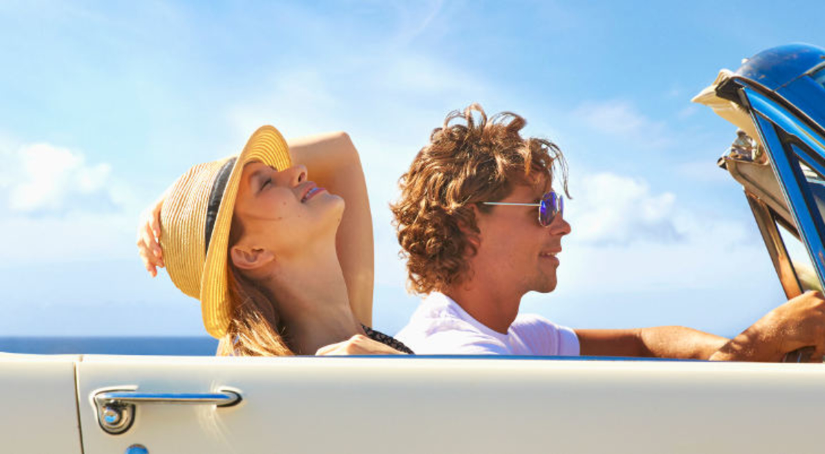 couple driving a white convertible at the coast