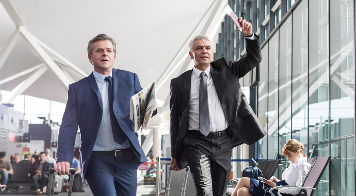 Two men running  through the airport for their flight