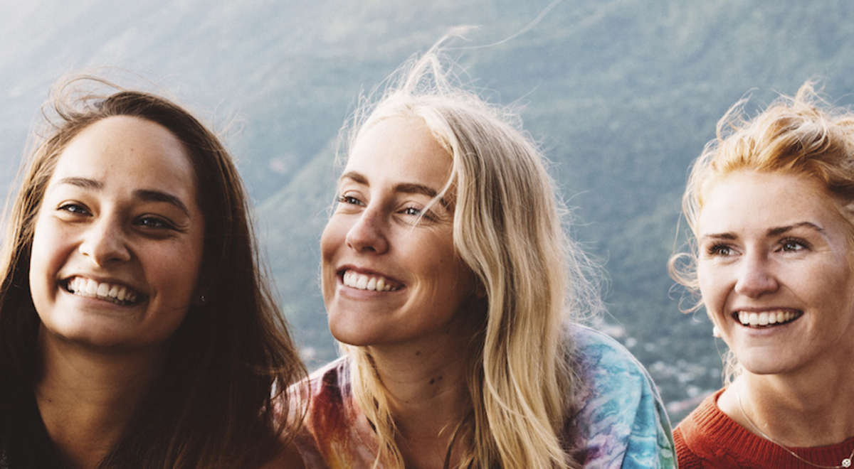Three ladies taking a photo with a mountain in the background