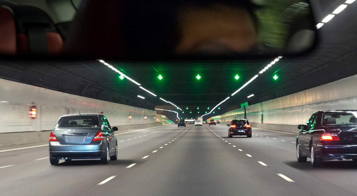 A view of cars driving through a tunnel from the point of view of a driver of the car at the rear