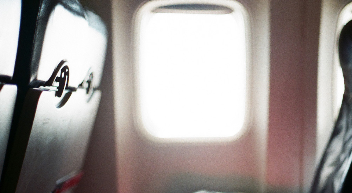 A row of seats on an airplane with sunlight coming in from the window