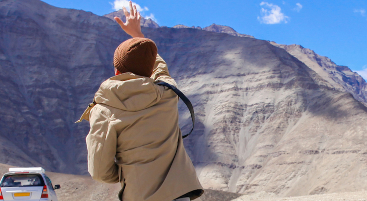 Person waving at a car drive off into the mountains