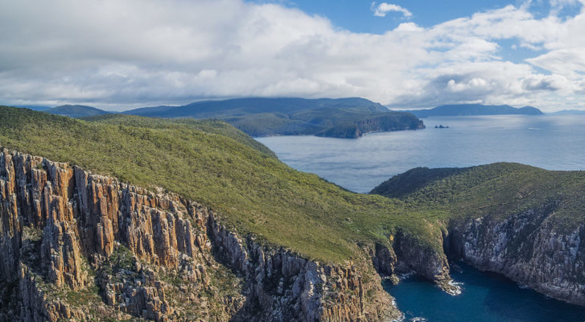 A photo of the ocean with a huge rock formed island 