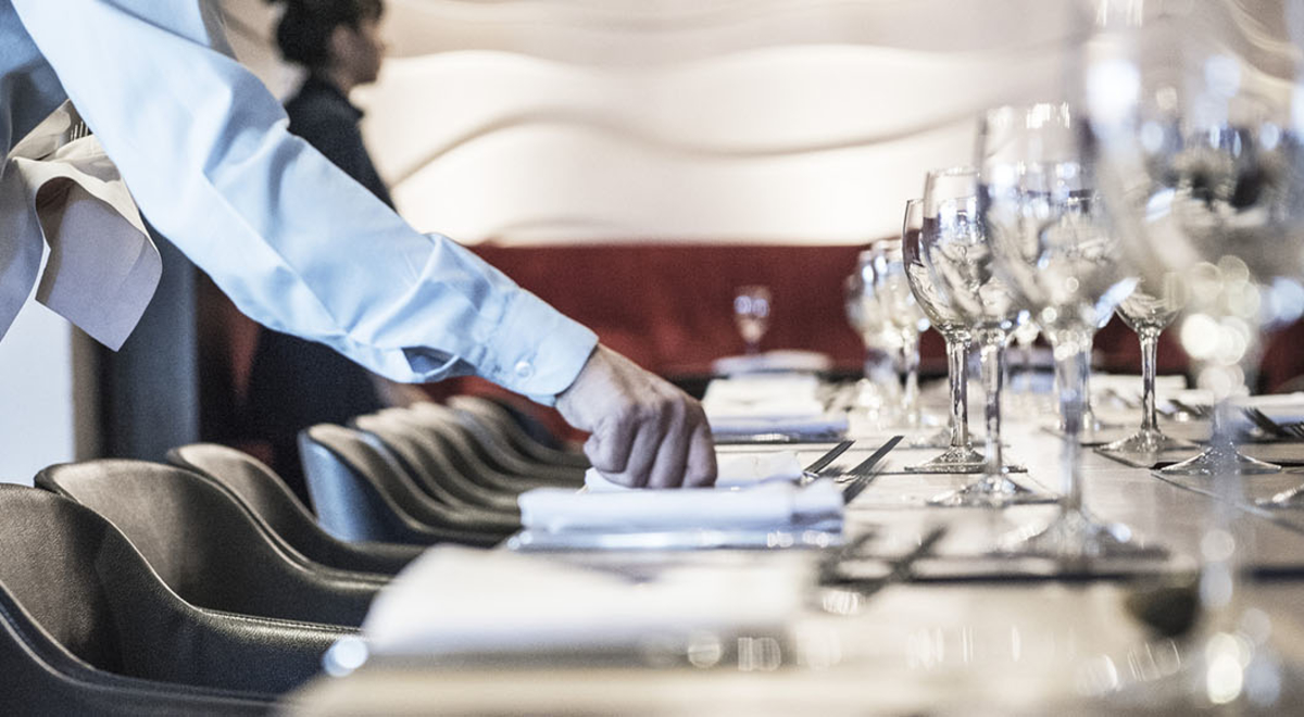 A waiter in black and white setting the table 