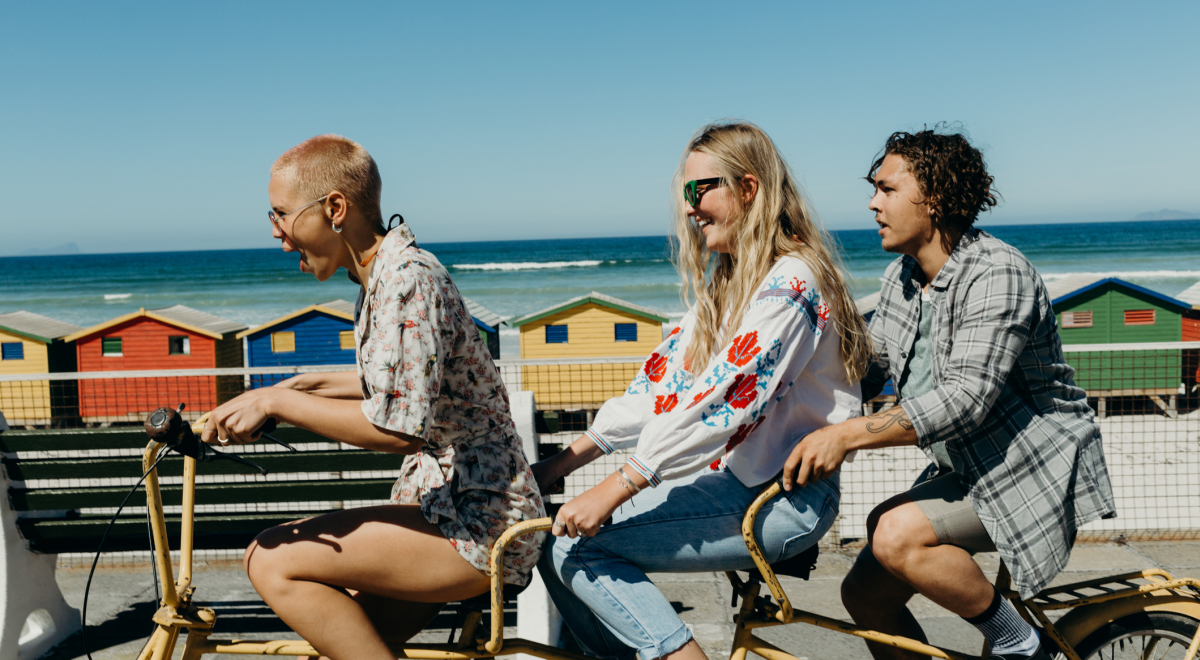 Friends travelling together on a three person bike 