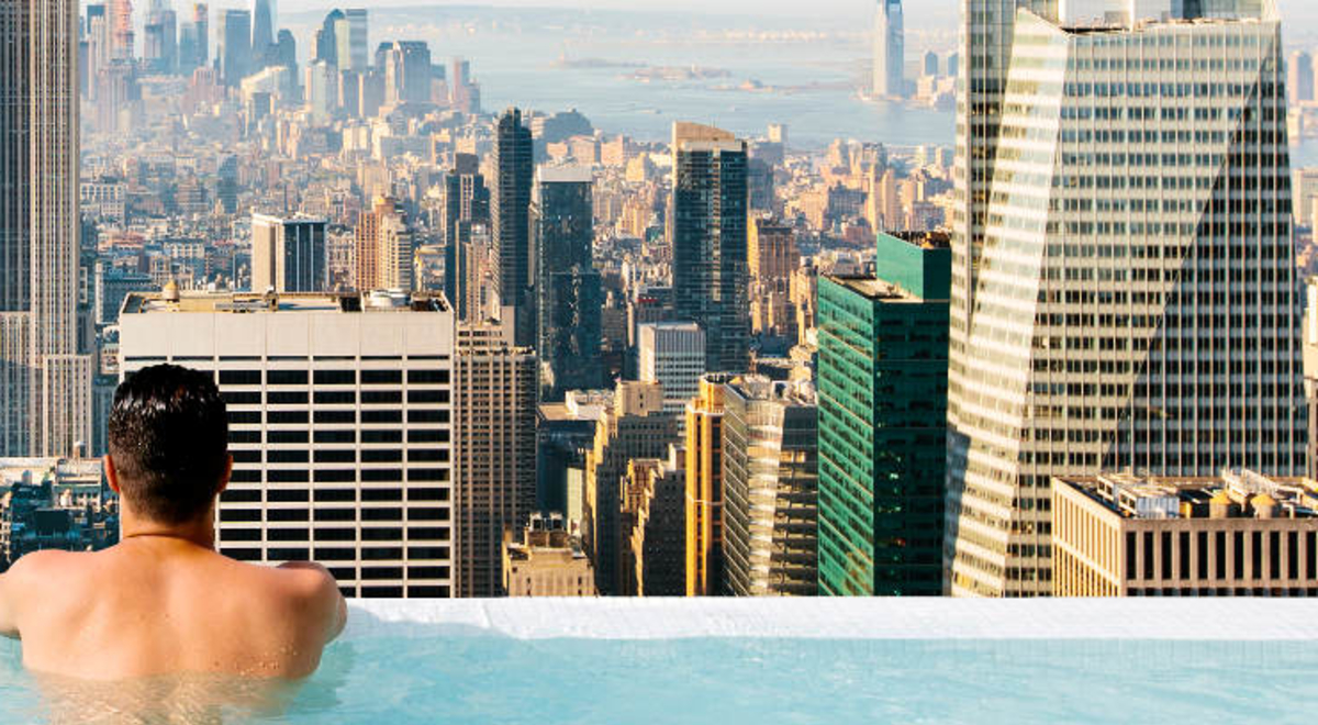 Man lounging on the edge of an infinity pool on top of a building