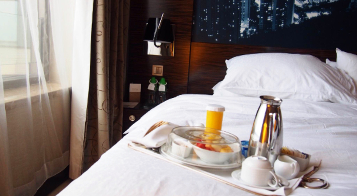 Tray with breakfast and drinks on a hotel bed 