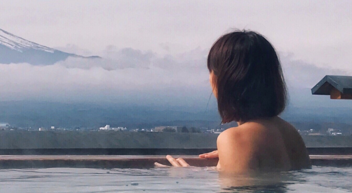 Woman swimming in spa looking out to mountain view 