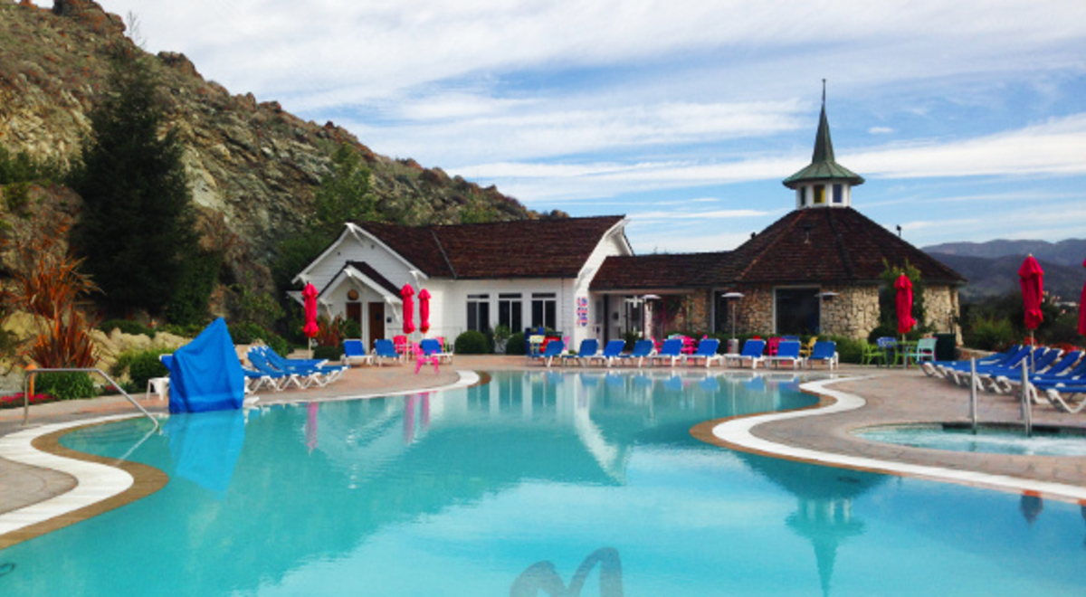 a big pool with blue lounge reclining pool chairs and red umbrellas