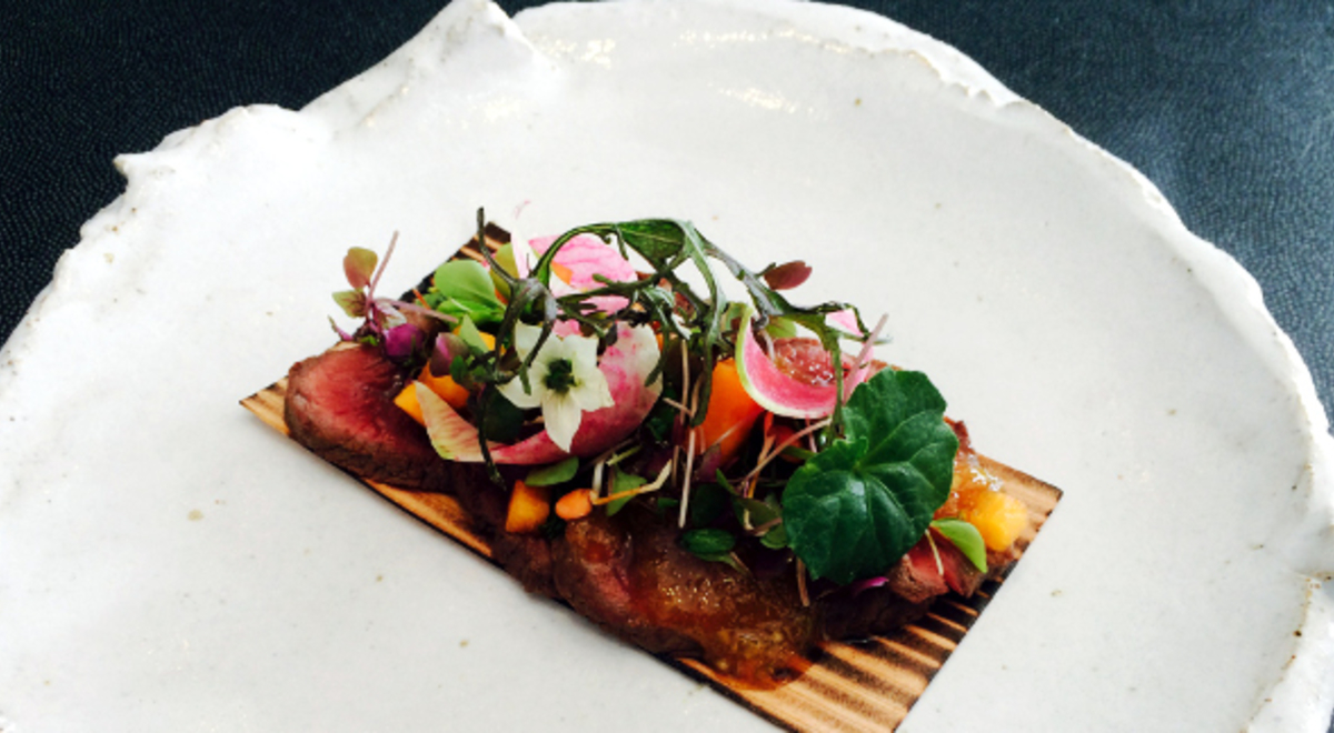A Noosa meat and wasabi dish garnished with flowers and some greens